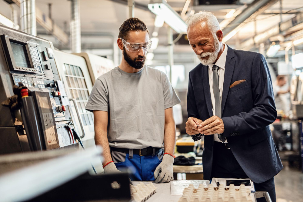 Executive reviewing production with a CNC machine operator on the factory floor